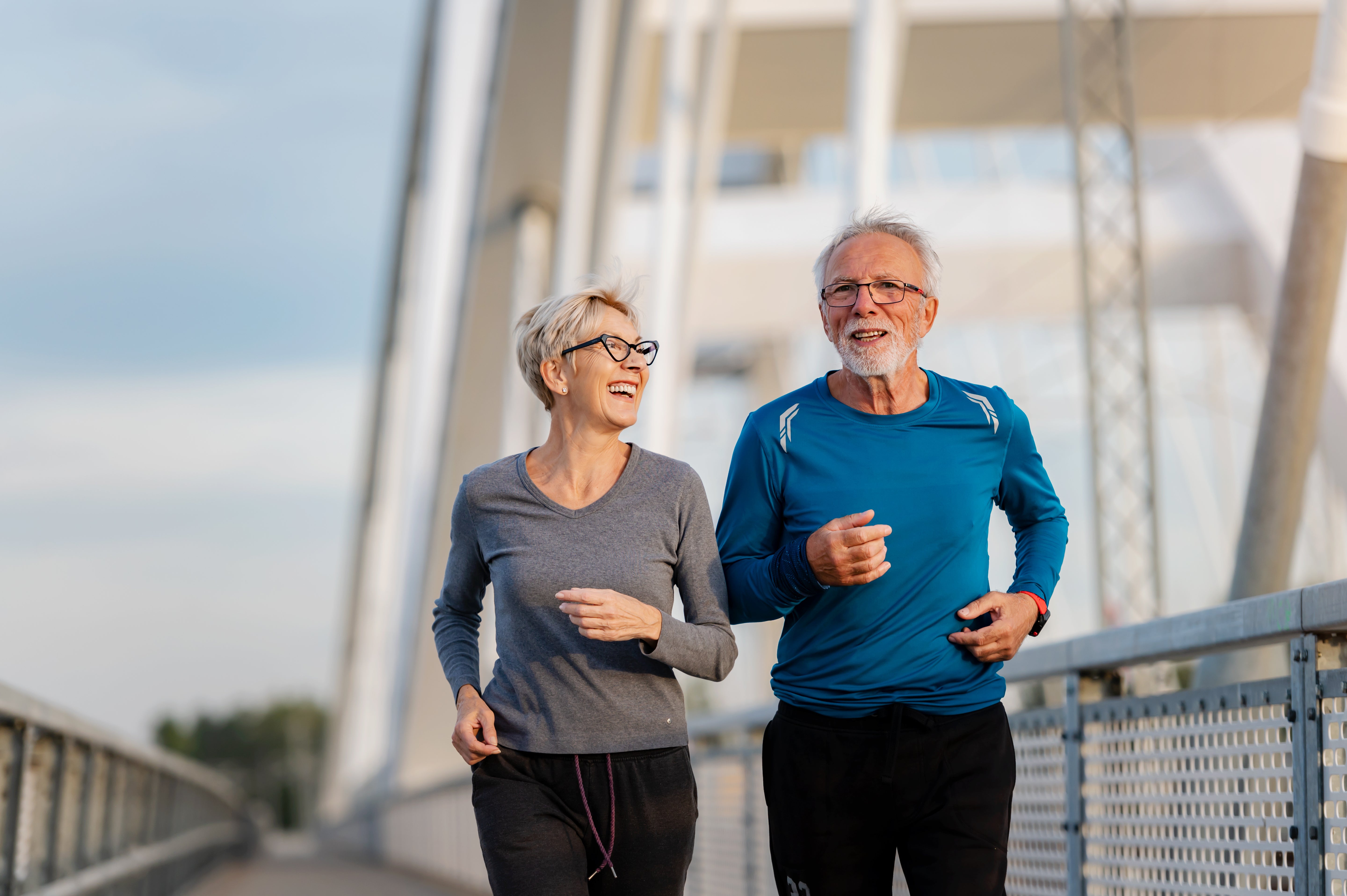 Two vibrant seniors, male and female, jogging across a bridge cardiovascular health and longevity