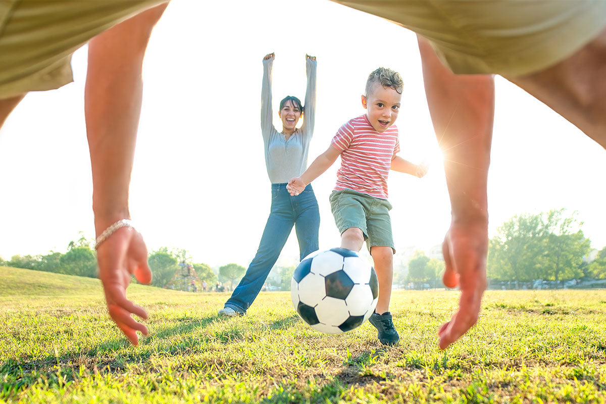 Father and mother with young child having family time playing soccer for heart health and longevity